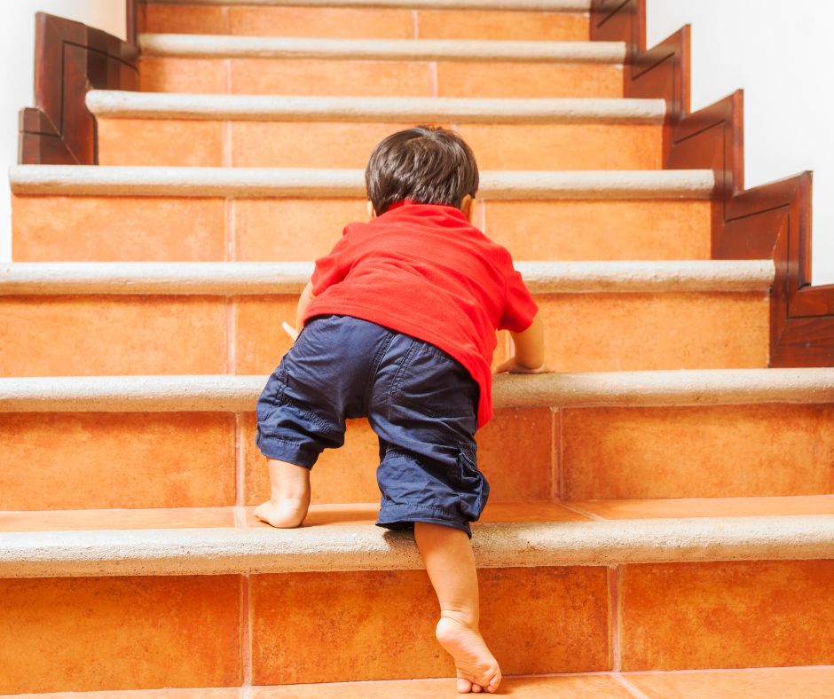 Auf diesem Bild sieht man ein Kleinkind von hinten, welches Treppen hinauf krabbelt.